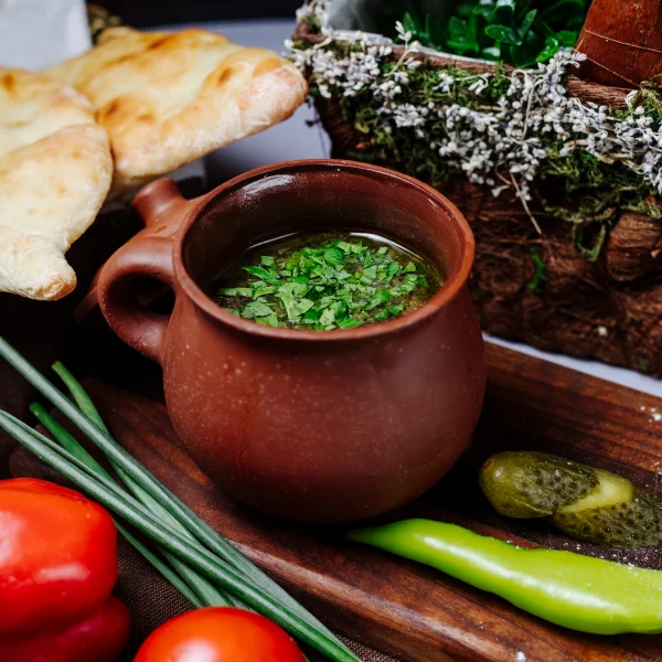 Un bol de soupe avec du pain, des tomates et des herbes fraîches.