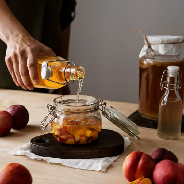 Une personne verse une boisson dans un pot en verre, contenant du sirop d'érable.