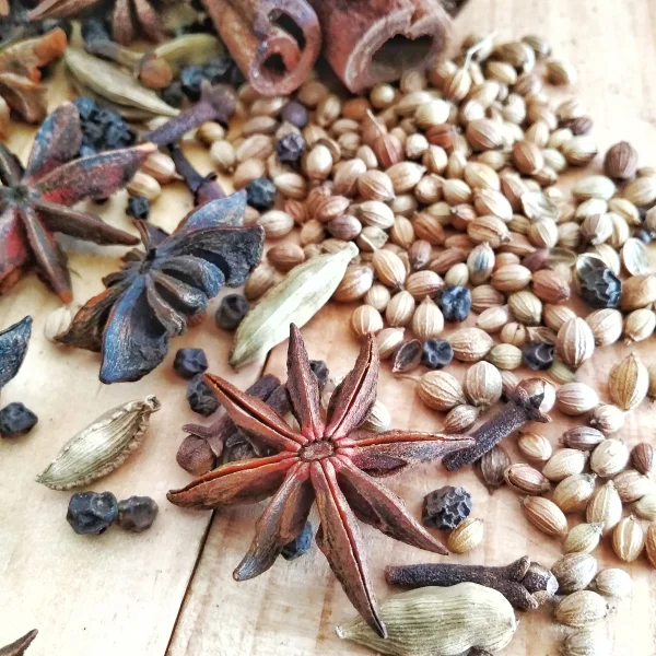 Épices et herbes variées disposées sur une table en bois, créant une ambiance chaleureuse et naturelle.
