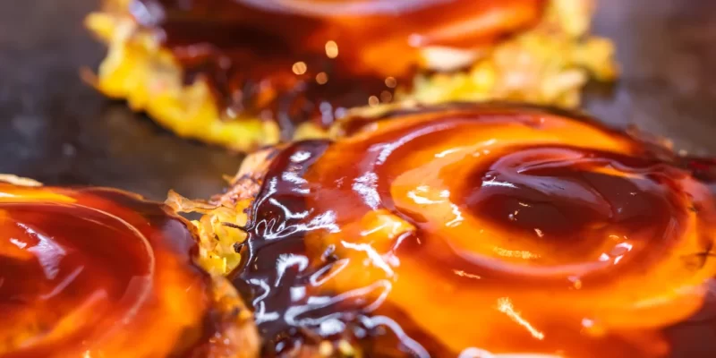 Gros plan sur trois donuts garnis de sauce, mettant en valeur leur texture et leur appétissant aspect.