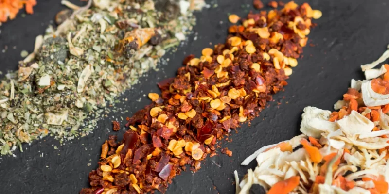 Une variété d'épices et d'herbes finement disposées sur une ardoise noire.