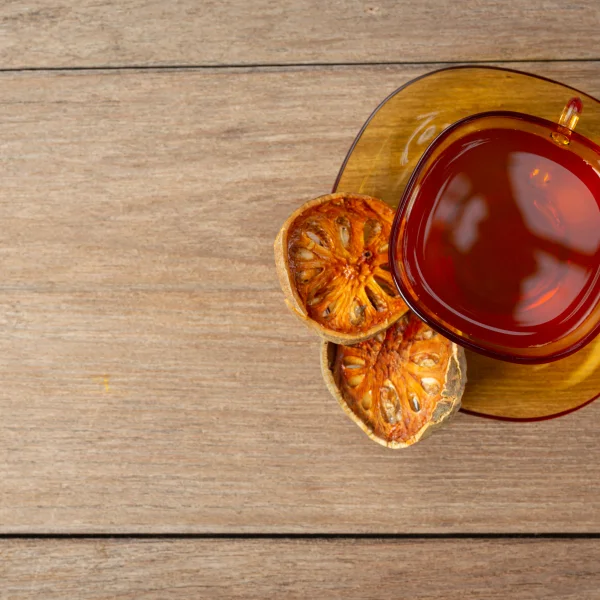 Une tasse de thé et une tranche d'orange posées sur une table en bois.