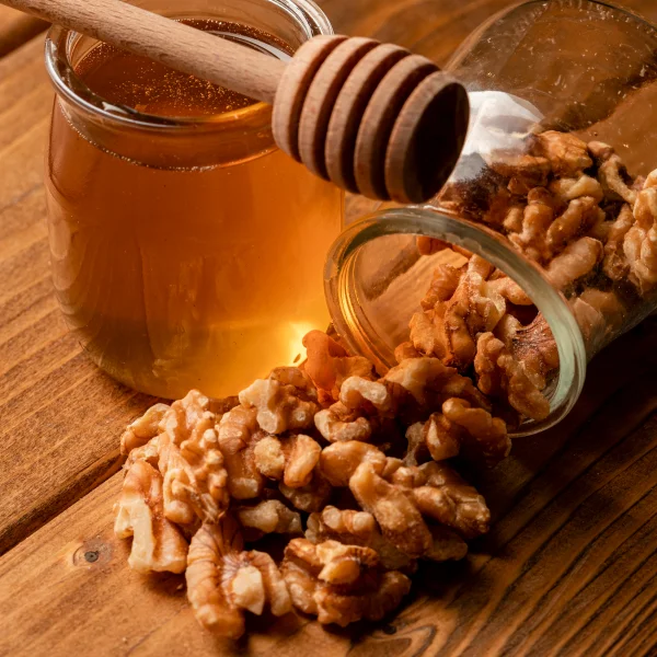 Noix et miel disposés sur une table en bois, créant un mélange appétissant et naturel.